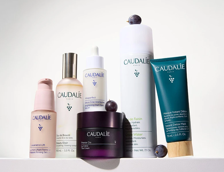 Her ses CAUDALIE hudplejeprodukter – serum, creme og mist i forskellige flasker på en lys baggrund.