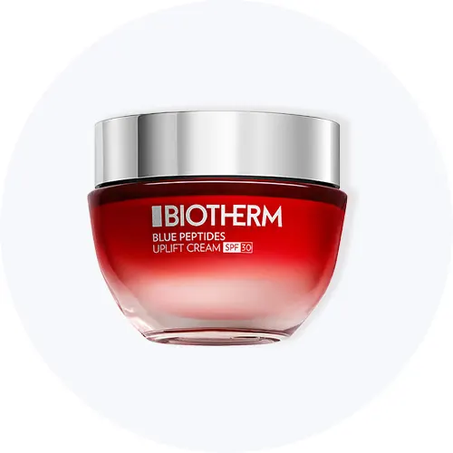 Her ses Biotherm Blue Peptides Uplift Cream SPF 30 i en rød krukke på en lysegrå cirkel.