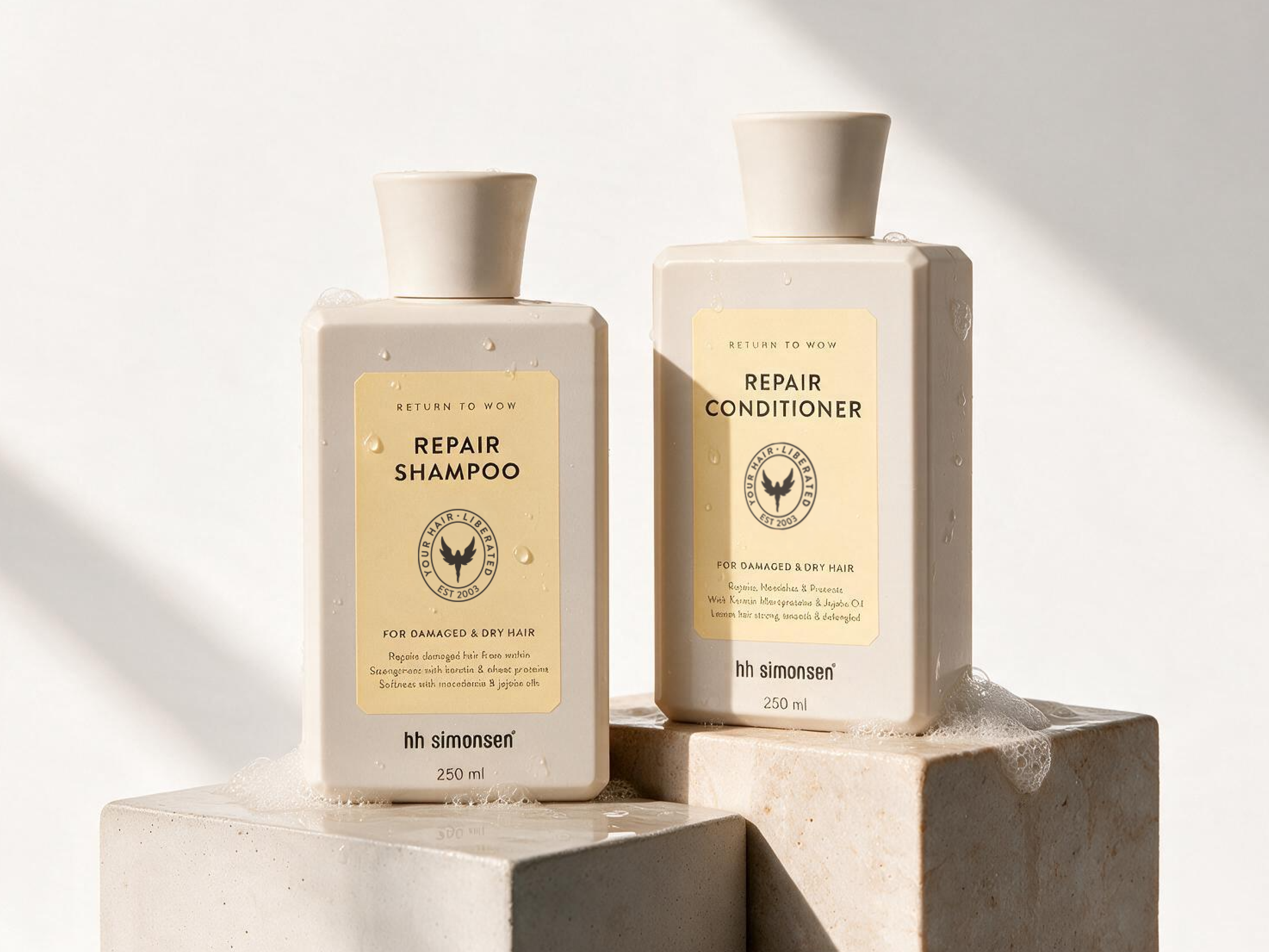 To hh simonsen Repair Shampoo og Conditioner flasker, 250 ml, til skadet og tørt hår, vist på stenblokke med vanddråber.
