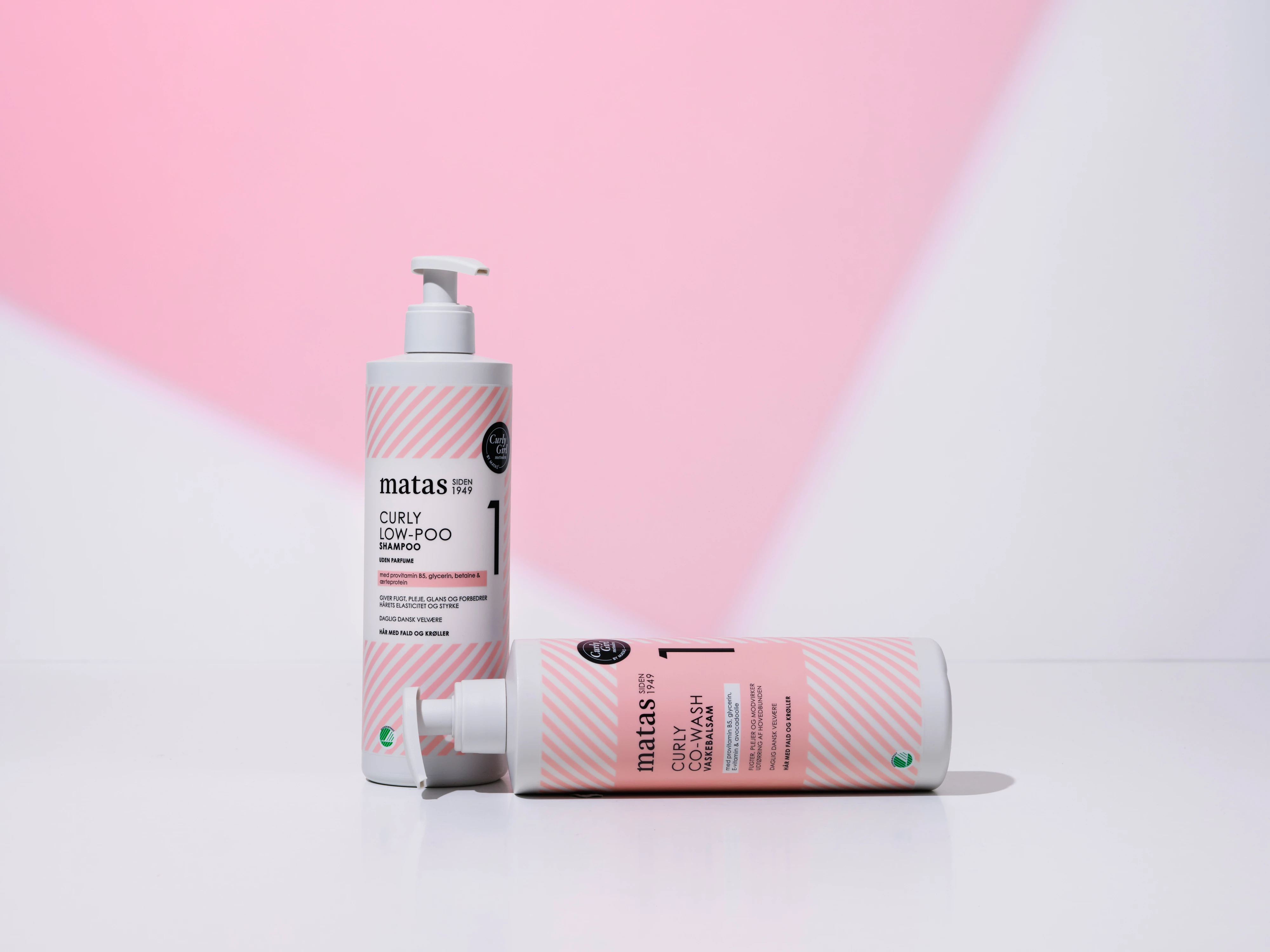 Her ses Matas Striber Curly Low-Poo Shampoo og Curly Co-Wash på en lys baggrund med et lyserødt grafisk farvefelt.