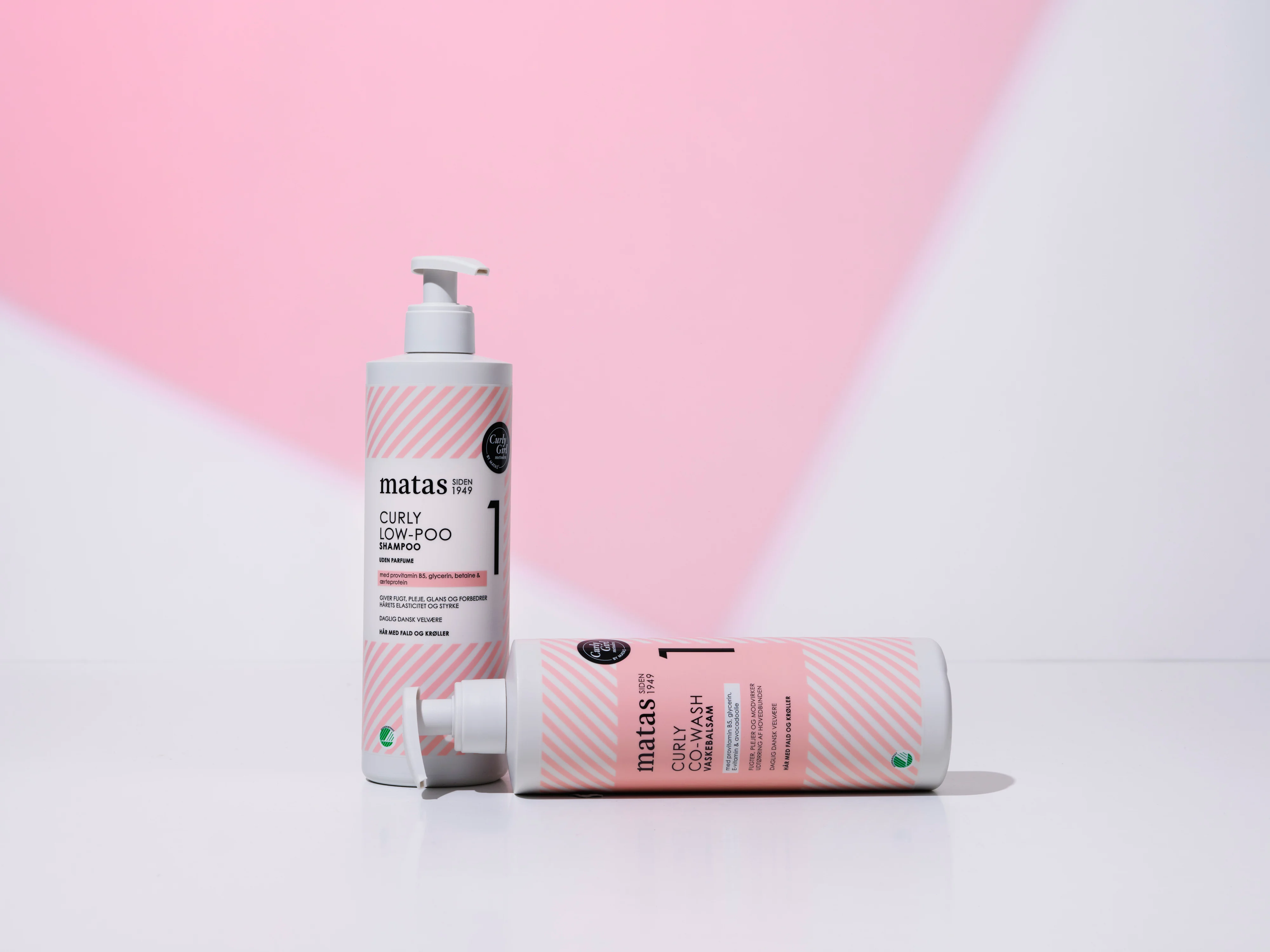 Her ses Matas Striber Curly Low-Poo Shampoo og Curly Co-Wash på en lys baggrund med et lyserødt grafisk farvefelt.