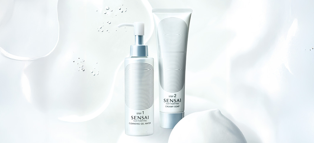 Her ses SENSAI renseprodukter – cleansing gel og creamy soap på en lys baggrund med vand og skum.