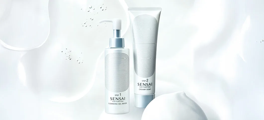 Her ses SENSAI renseprodukter – cleansing gel og creamy soap på en lys baggrund med vand og skum.