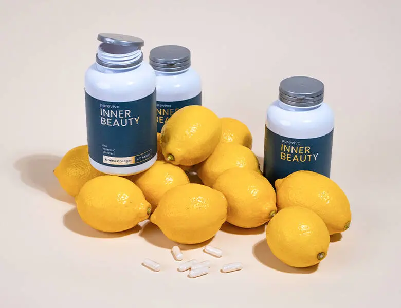 Her ses tre bøtter med Inner Beauty kosttilskud. De står på en lys baggrund omgivet af citroner og piller