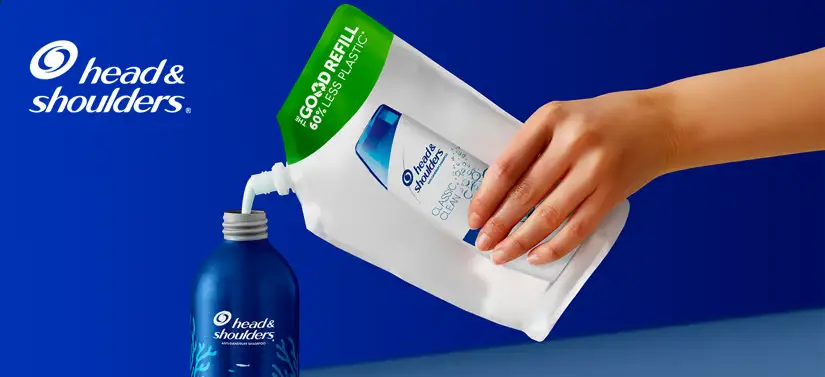 Her ses en mørkeblå baggrund med et hvidt logo i venstre venstre hjørne. Der ses desuden en arm, som holder et hvidt produkt, som bliver hældt hen i et blåt produkt.