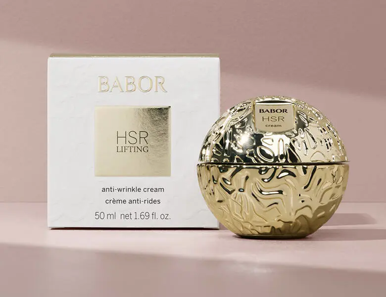 Her ses en lyserød baggrund med et stort guld produkt fra Babor.