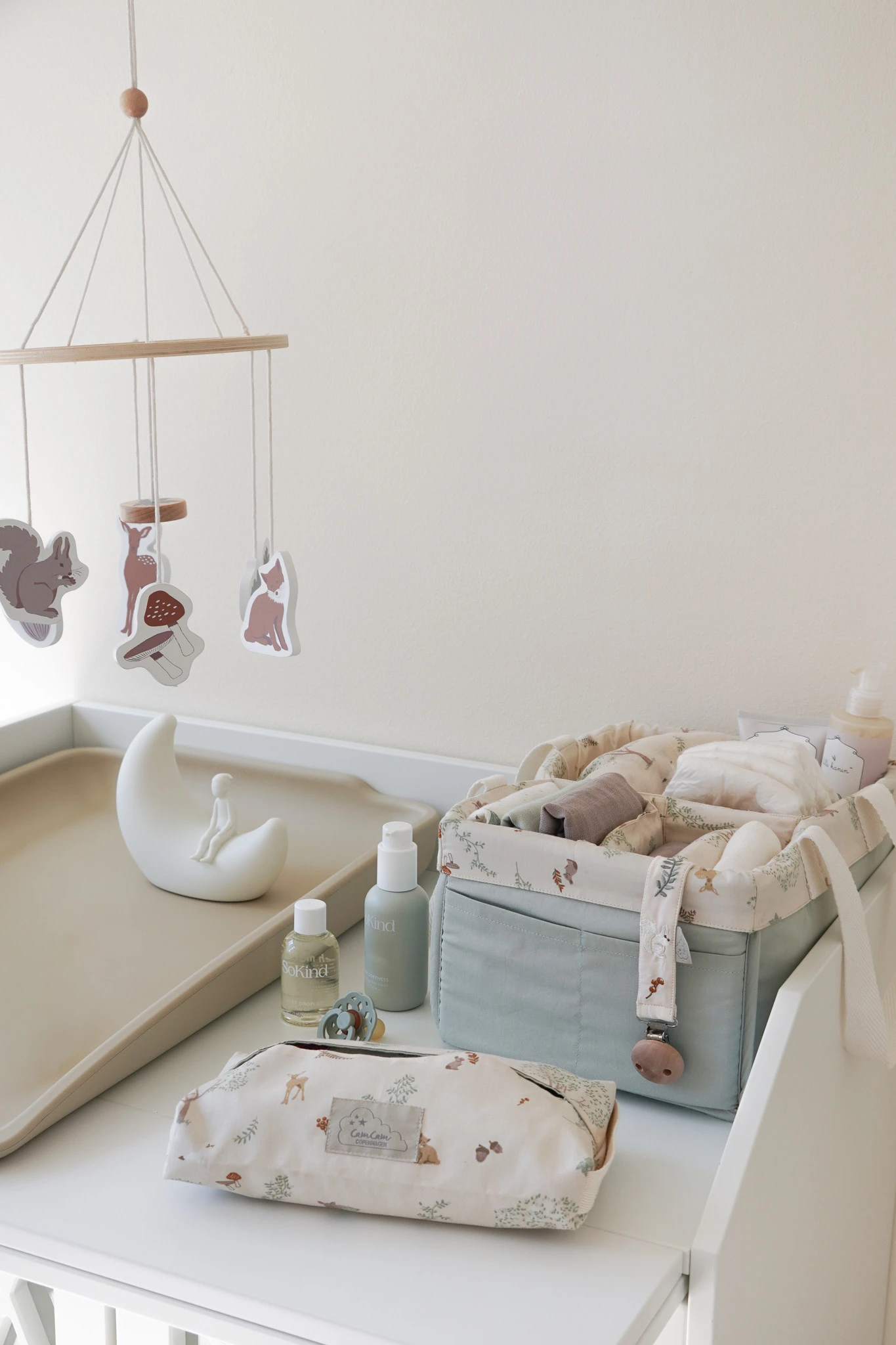 Puslebord med skovdyrsmobil, månelampe, SoKind og Kind babyplejeprodukter og CamCam stofopbevaring.