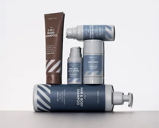 Her ses Matas Striber produkter til mænd – shampoo, deodorant og ansigtsserum i blå og brun emballage på en lys baggrund.