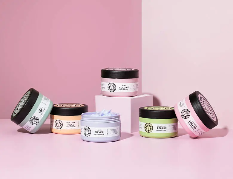 Her ses en lyserød baggrund med seks forskellige Maria Nila produkter i forskellige farver.
