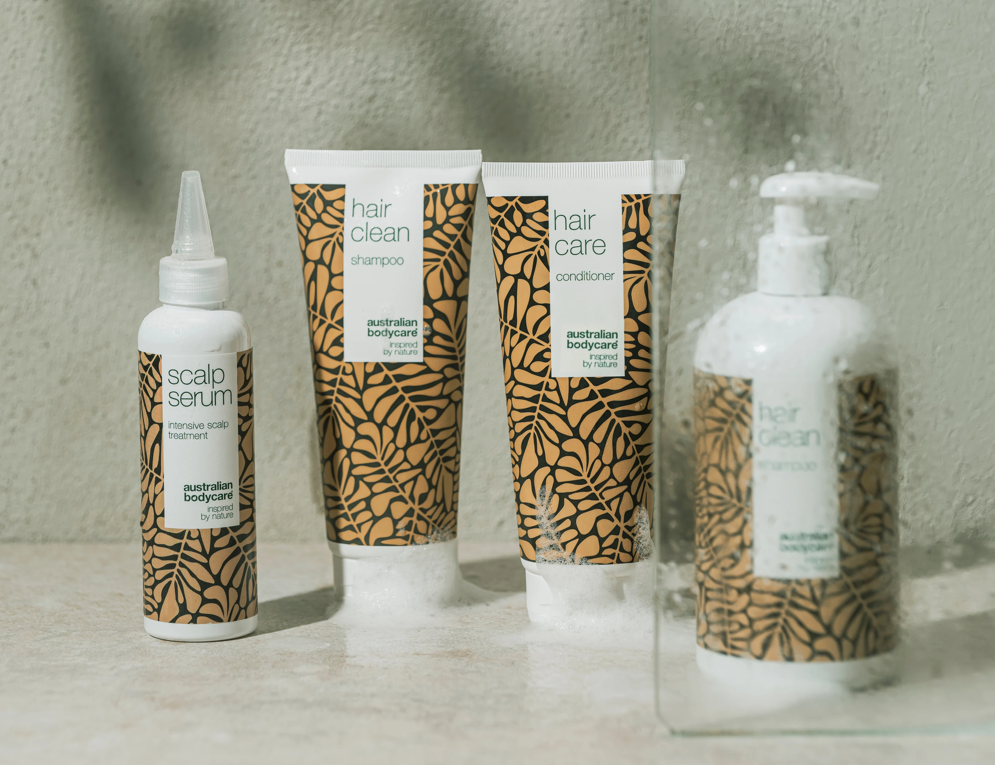 Her ses australian bodycare hårprodukter – shampoo, conditioner og scalp serum placeret i et badeværelsesmiljø.