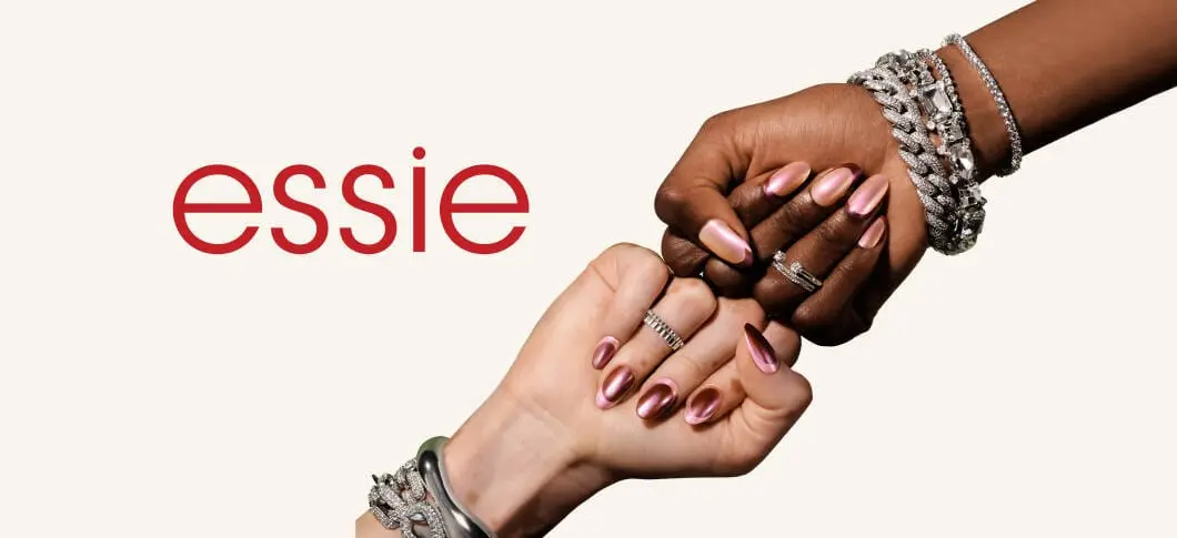 Her ses en beige baggrund og "essie" skrevet med rød. Der ses to hænder holdt mod hinanden så man kan se deres neglelak på.