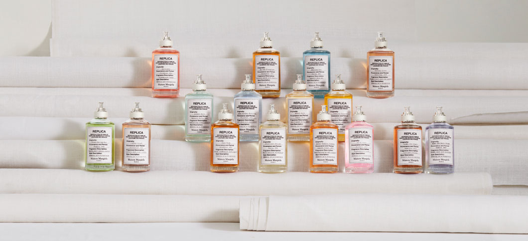 Her ses flere Maison Margiela Replica-parfumer opstillet i rækker på forskellige trin og med en lys baggrund.