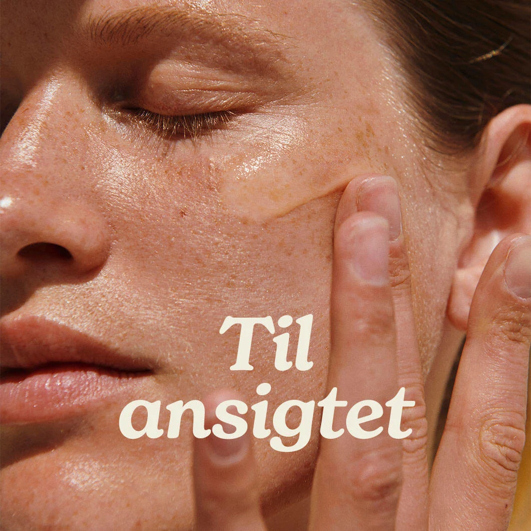 Her ses et close up billede af en kvindes ansigt. Hun er ved at påføre creme på kinden. Forrest står der med hvid "Til ansigtet".