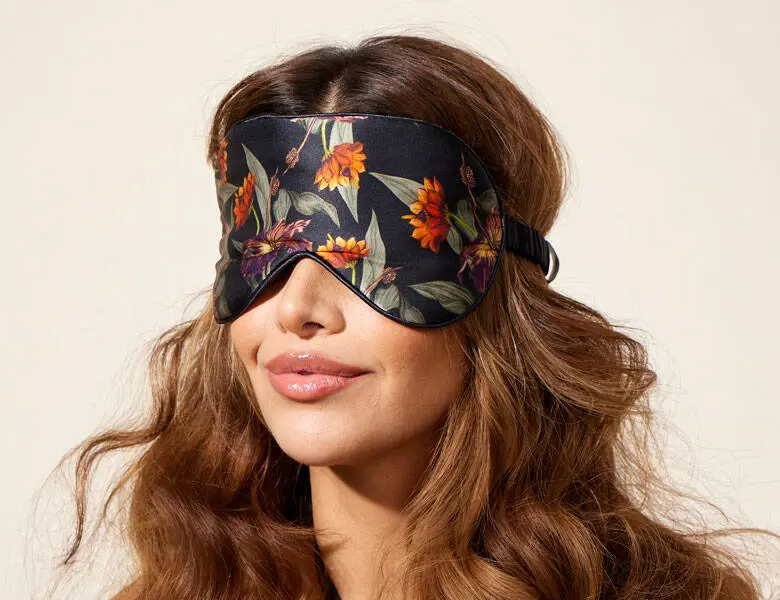 Her ses ansigtet af en kvinde med en mørk sovemaske på. Baggrunden er lys.