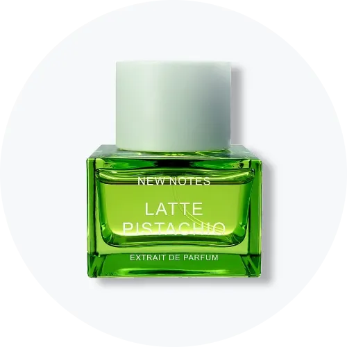 Her ses et billede af en parfumeflakon fra New Notes placeret centralt mod en lys, rund baggrund. På flakonen står teksten “LATTE PISTACHIO EXTRAT DE PARFUM”. Flakonen er i grøn nuance med lyst låg.
