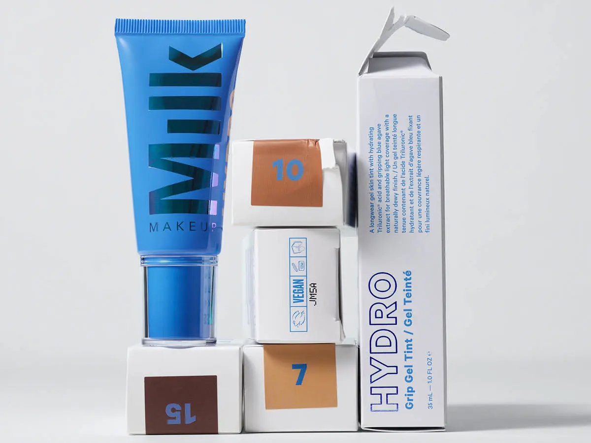 Her ses Milk Makeup Hydro Grip Gel Tint sammen med emballager i forskellige nuancer. Den blå tube og de hvide æsker er stablet i en grafisk opstilling mod en lys baggrund.