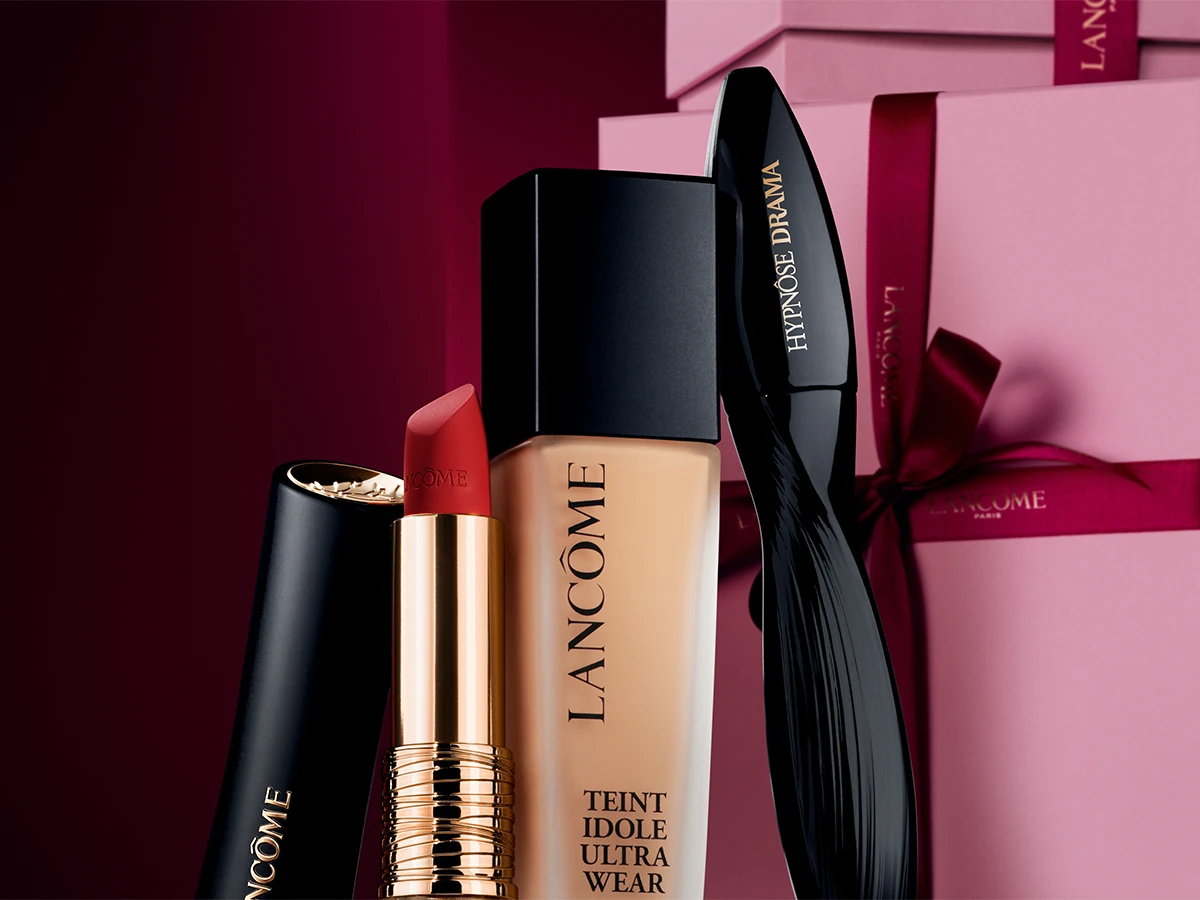Rød Lancôme læbestift, Lancôme Teint Idole Ultra Wear foundation og Lancôme Hypnôse Drama mascara foran pink gaveæsker.