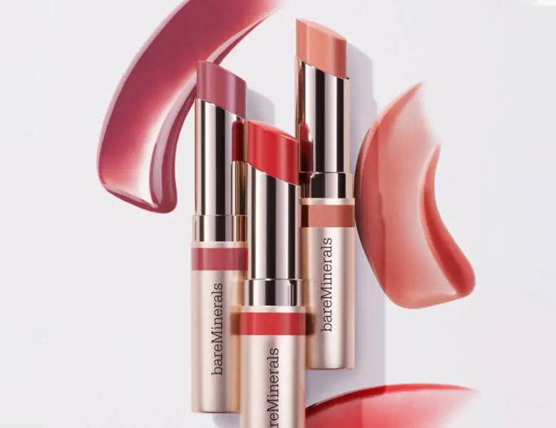 Her ses et billede af tre bareMinerals produkter til læberne. Baggrunden er produkterne smurt ud på noget hvidt.
