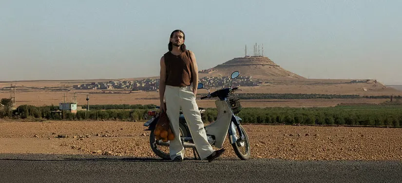 Her ses en mand, som står foran en motorcykel ude midt i ingenting. 