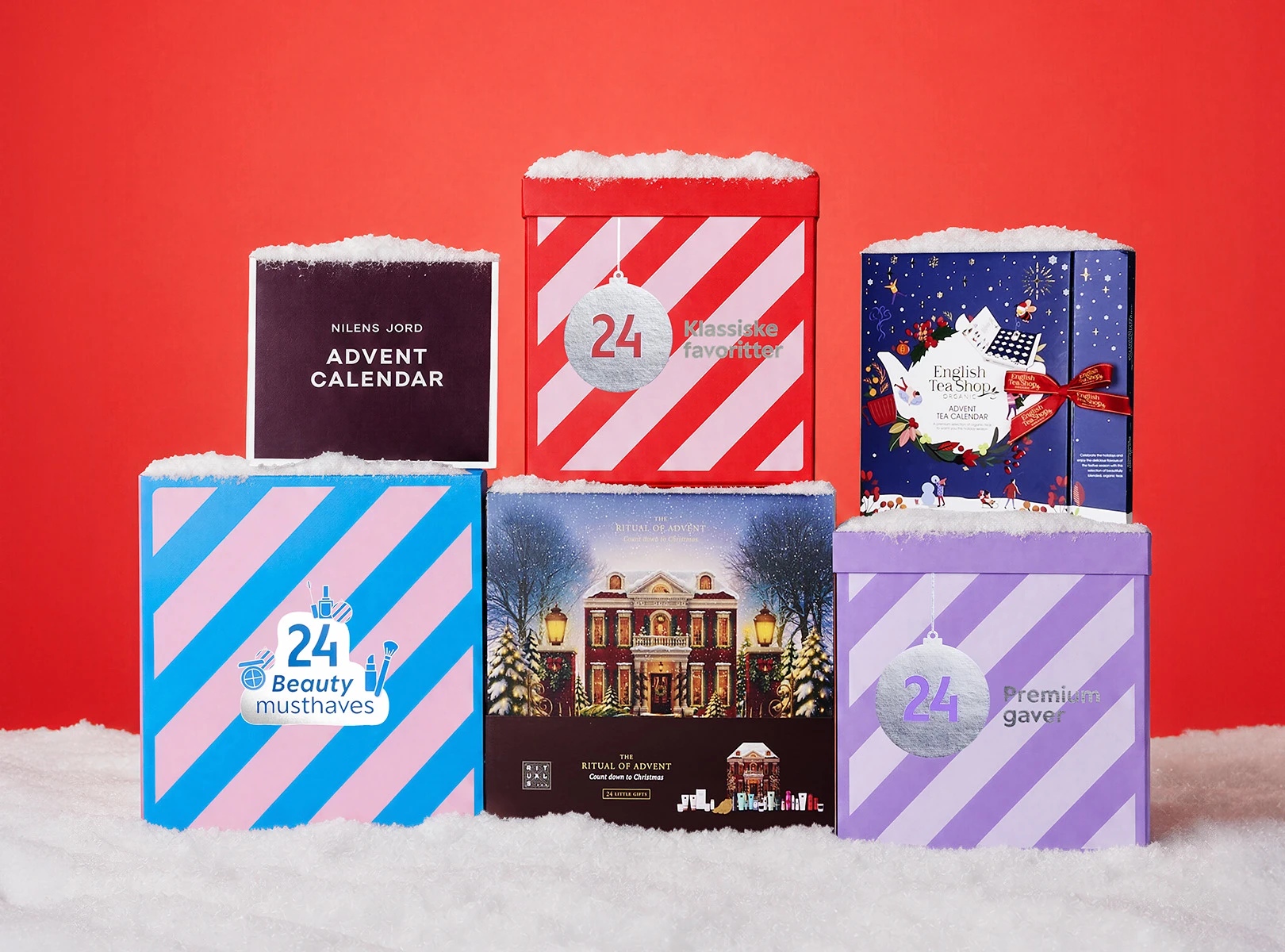 Seks forskellige julekalendere dækket med sne. Kalenderne omfatter Nilens Jord, Klassiske favoritter, English Tea Shop, 24 Beauty musthaves, The Ritual of Advent og 24 Premium gaver.