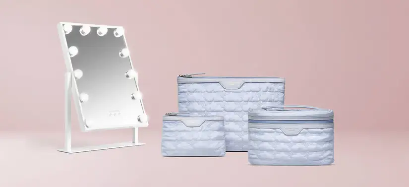 Her ses en lyserød baggrund med tre blå toilettasker og et spejl med lys.