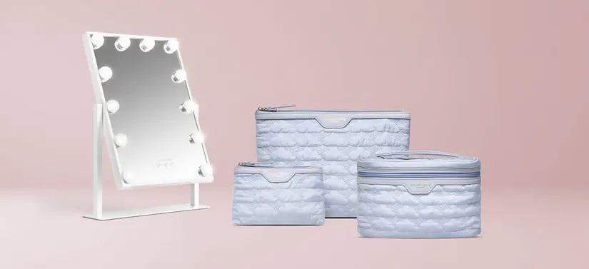 Her ses en lyserød baggrund med tre blå toilettasker og et spejl med lys.