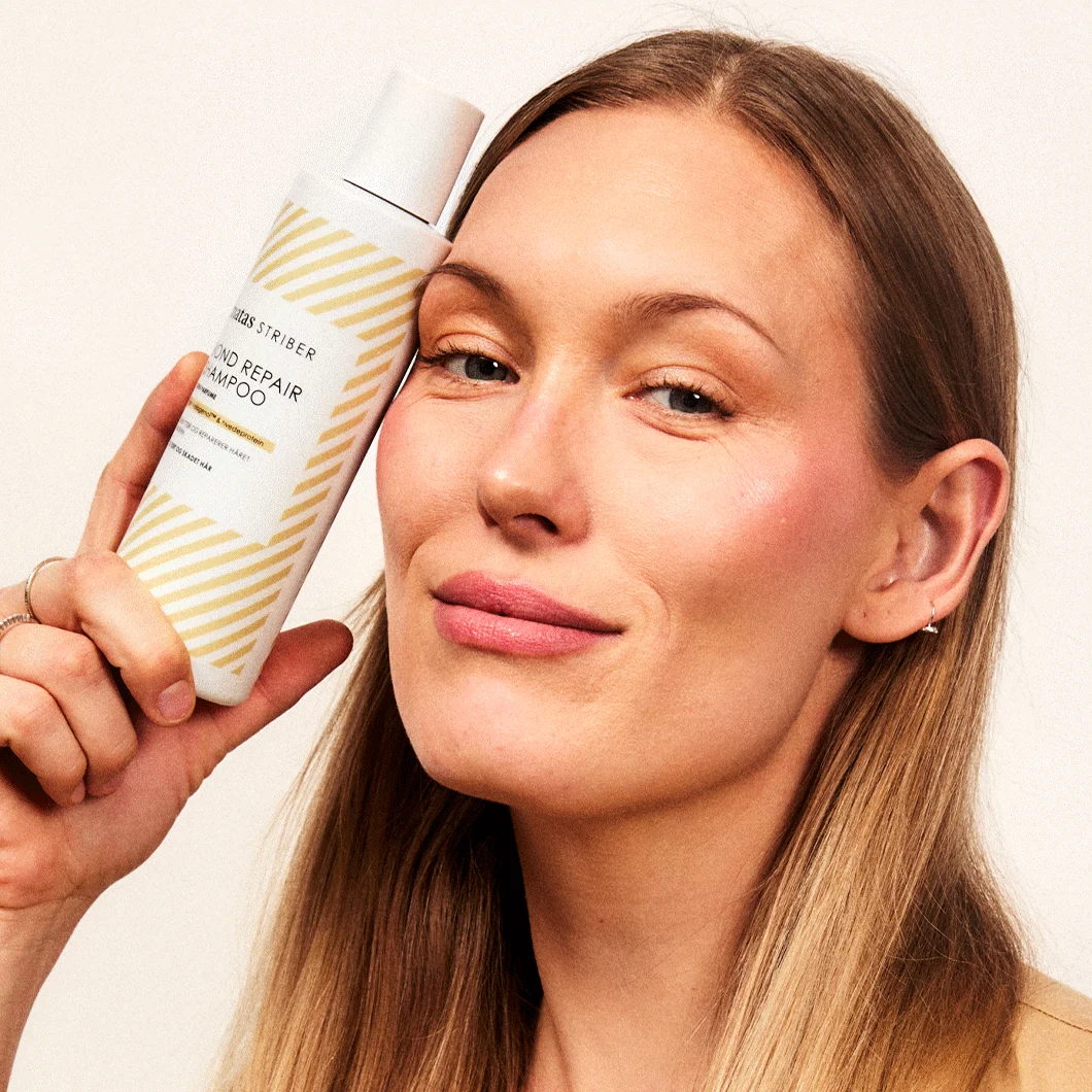 Her ses en kvinde. Hun holder et Bond Repair produkt op til ansigtet.