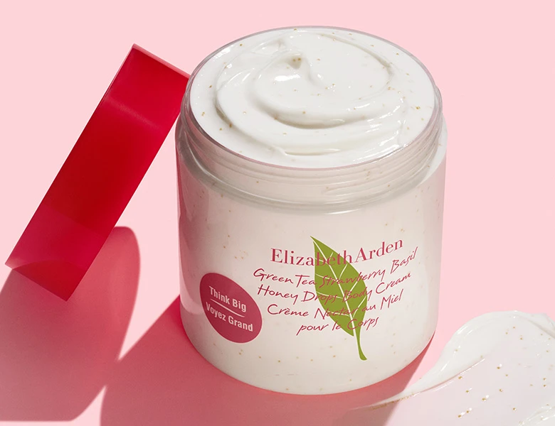 Her ses en Elizabeth Arden body cream i en krukke med creme på en lyserød baggrund.