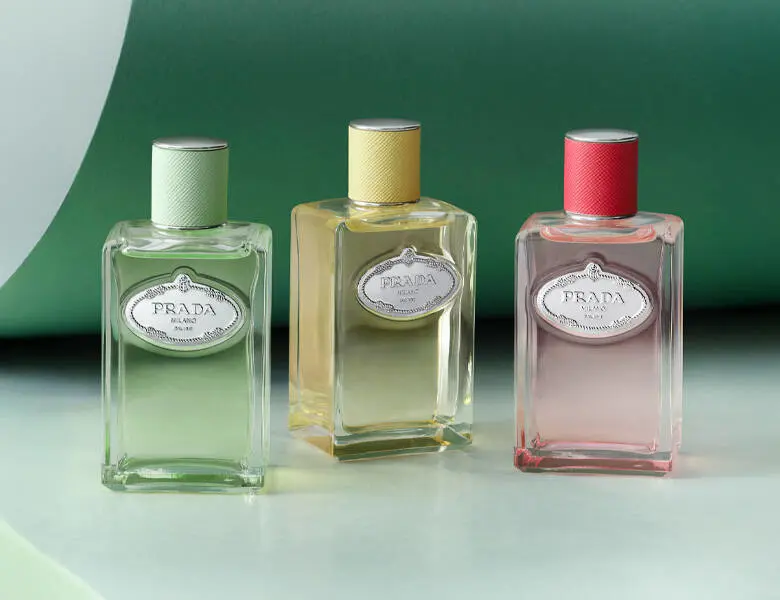 Her ses en grøn baggrund med tre forskellige Prada produkter - et grønt, et gult og et lyserødt.