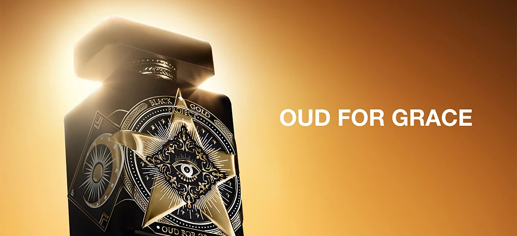 Her ses Initio Oud for Greatness i en sort parfumeflakon med detaljerede guldfarvede ornamenter og et øjesymbol på forsiden. Flakonen er oplyst af gyldent lys mod en varm orange baggrund, og til højre står teksten “Oud for Grace”.