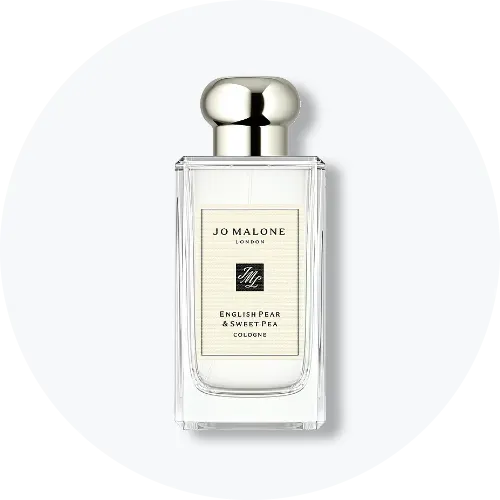 Her ses et billede af en parfumeflakon fra Jo Malone London placeret centralt mod en lys, rund baggrund. På flakonen står teksten “JO MALONE LONDON ENGLISH PEAR & SWEET PEA COLOGNE”. Flakonen er i klart glas med sølvfarvet låg.