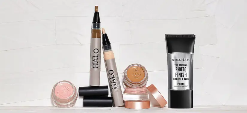 Her ses en lys baggrund med en masse forskellige Smashbox makeupprodukter. 