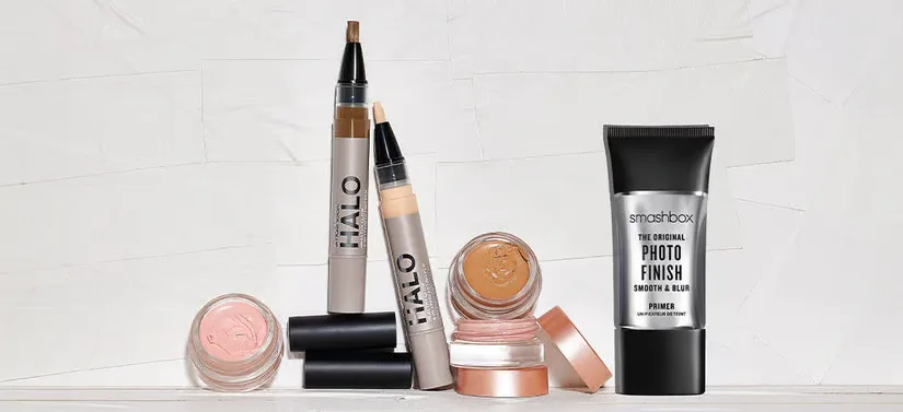 Her ses en lys baggrund med en masse forskellige Smashbox makeupprodukter. 