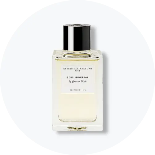 Her ses et billede af en parfumeflakon fra Essential Parfums placeret centralt mod en lys, rund baggrund. På flakonen står teksten “ESSENTIAL PARFUMS PARIS BOIS IMPÉRIAL by Quentin Bisch”. Flakonen er i klart glas med sort låg.