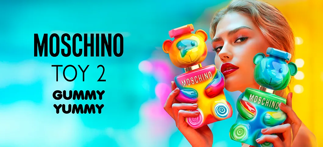 Her ses et billede med en person til højre, der holder to parfumeflakoner formet som bamser i farverige nuancer. Til venstre står teksten “MOSCHINO TOY 2 GUMMY YUMMY”.