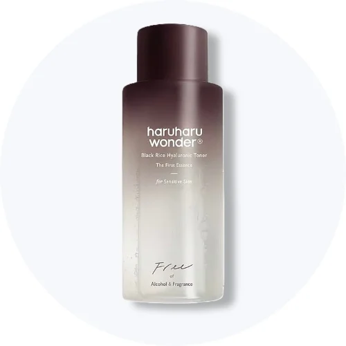 Her ses en Haruharu Wonder Black Rice Hyaluronic Toner Free i en brun og gennemsigtig flaske på en lys baggrund.