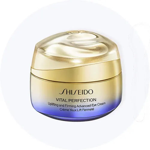 Her ses Shiseido Vital Perfection Uplifting and Firming Advanced Eye Cream i en gylden krukke med lilla bund på en lysegrå cirkel.