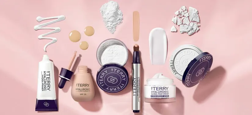 Her ses en masse By Terry produkter på en lyserød baggrund.