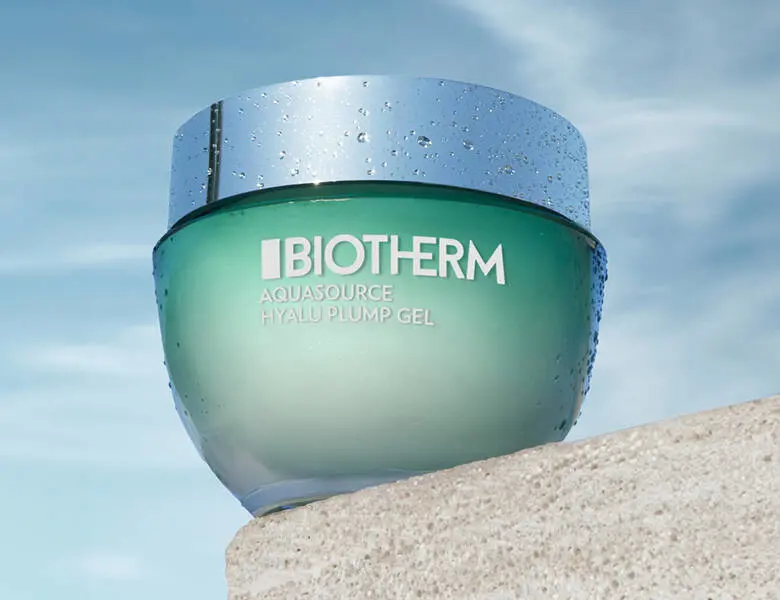 Her ses et grønt Biotherm produkt, som står på en sten med en blå himmel som baggrund.