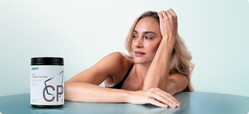 Kvinde læner sig mod et bord og ser til siden på lys blågrøn baggrund, mens en bøtte Puori Collagen Peptides står til venstre i billedet.