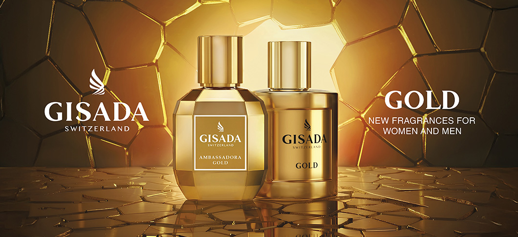 Her ses et billede med to parfumeflakoner fra Gisada placeret centralt mod en gylden baggrund med mønster. På flakonerne står “GISADA SWITZERLAND”, “AMBASSADORA GOLD” og “GOLD”. Til venstre står teksten “GISADA SWITZERLAND”, og til højre står “GOLD” samt “NEW FRAGRANCES FOR WOMEN AND MEN”.