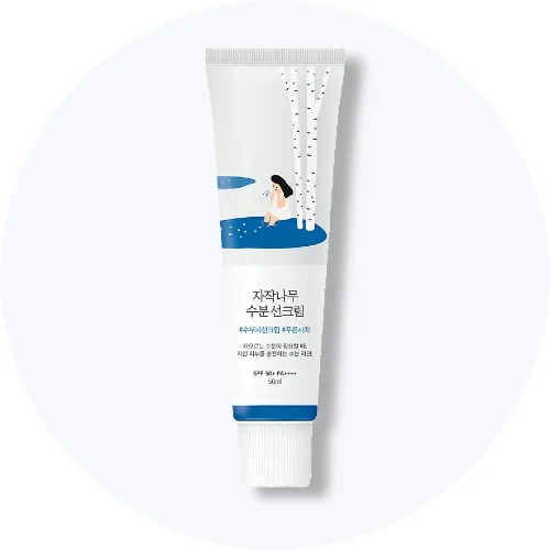 Her ses en ROUND LAB Birch Juice Moisturizing Sun Cream SPF 50+ i hvid og blå emballage på en lys baggrund.