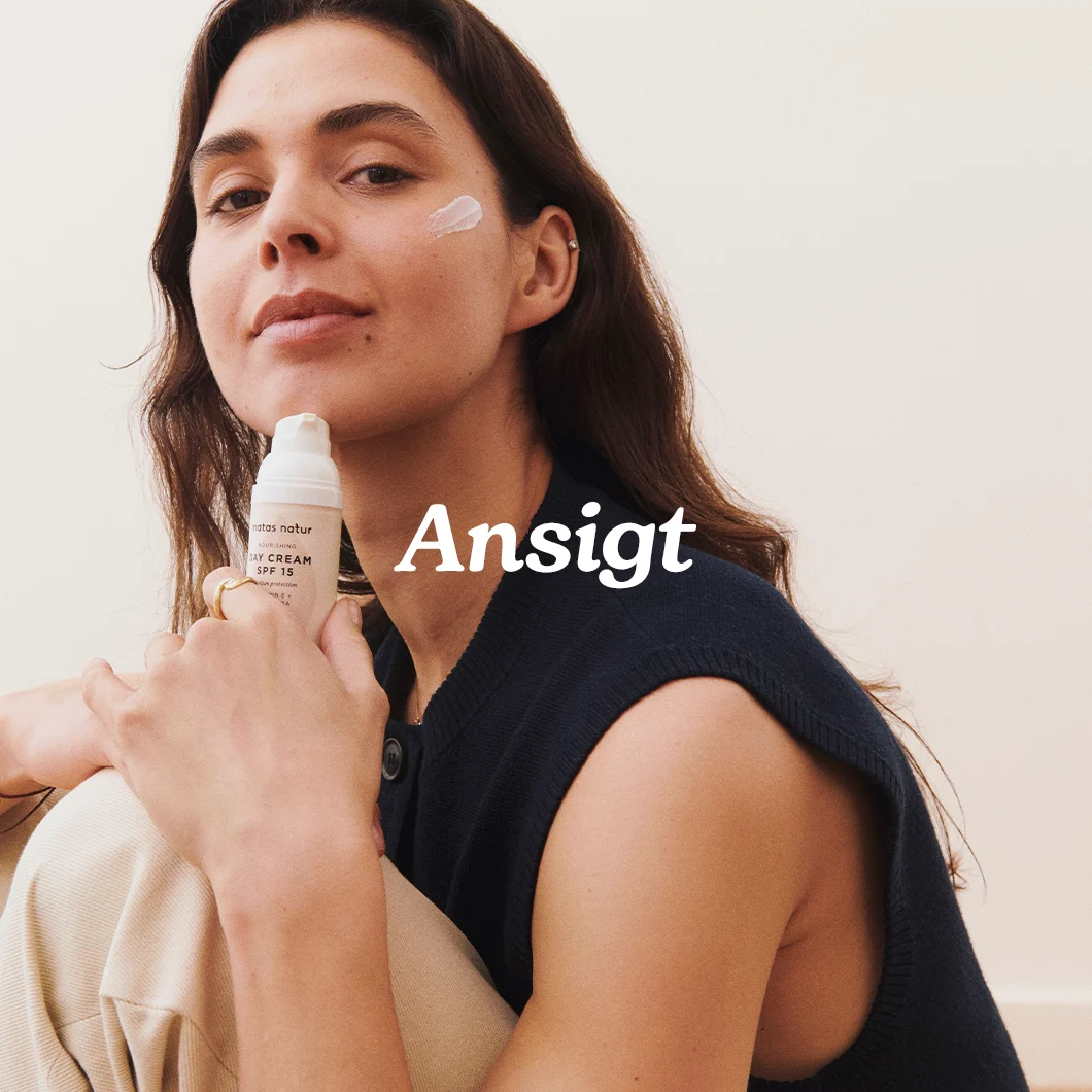 Her ses en kvinde, der holder en ansigtscreme fra Matas Natur med teksten “Ansigt” på en lys baggrund.