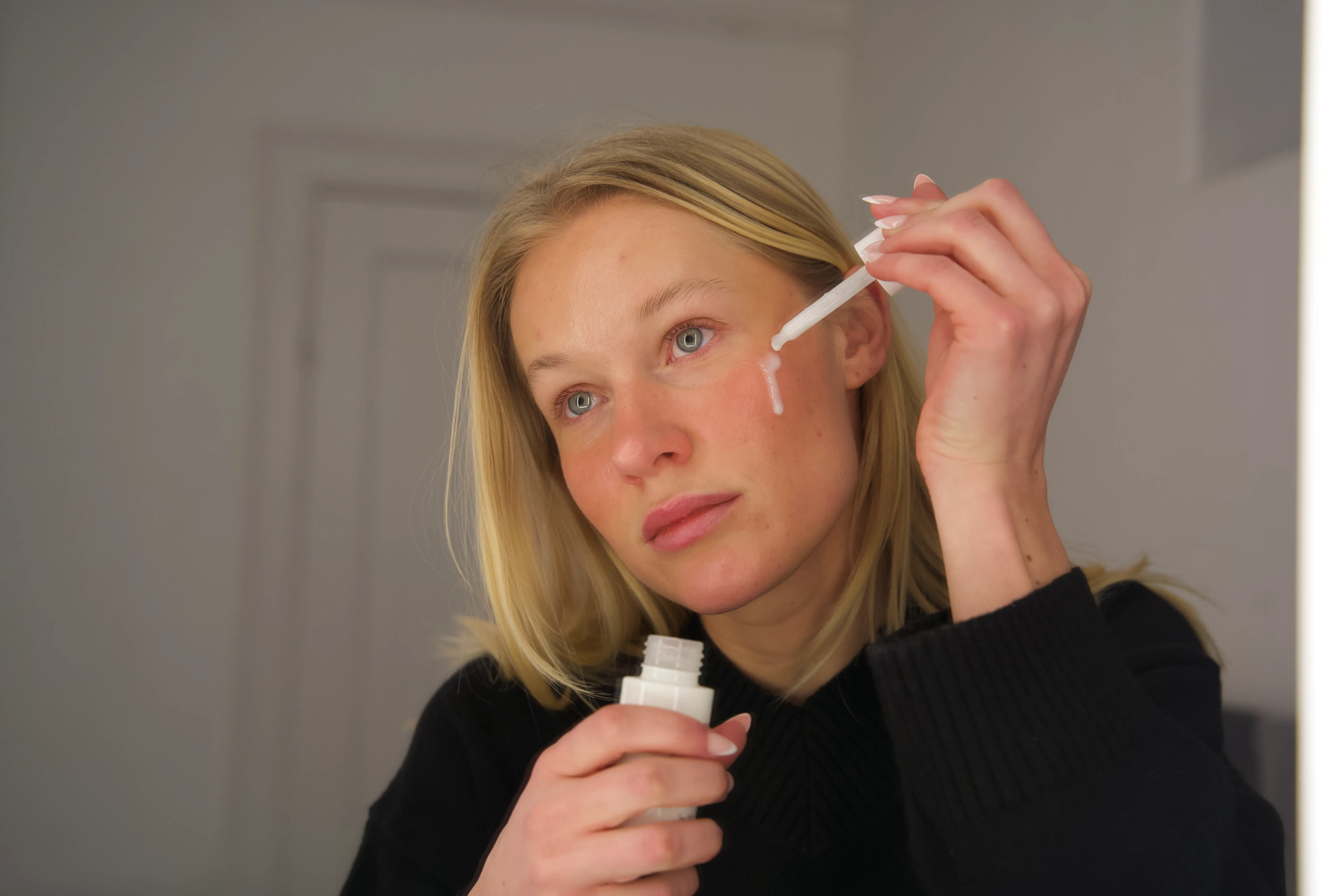 Kvinde, der påfører serum på sin kind