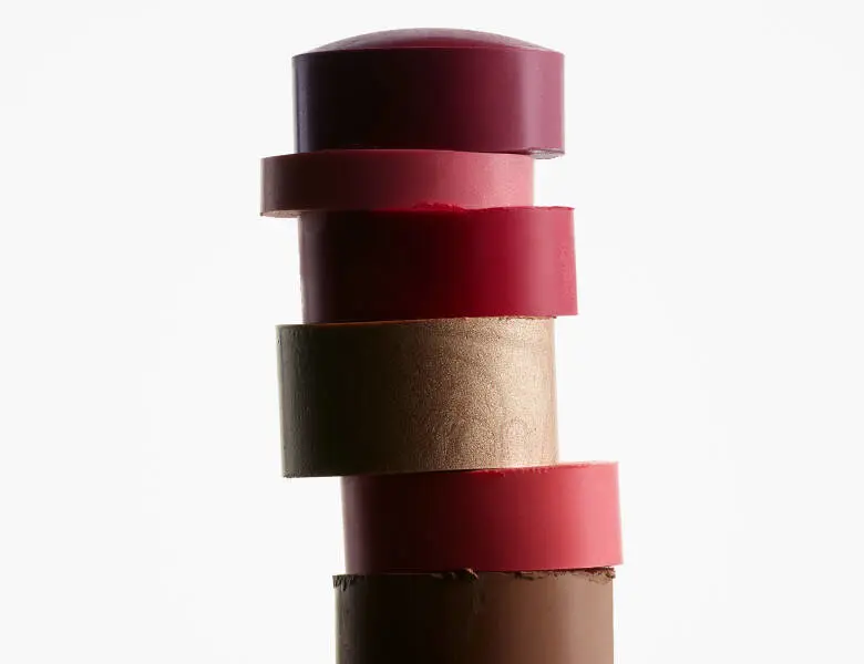 Her ses forskellige farvede makeup sticks stablet på hinanden. Baggrunden er hvid.