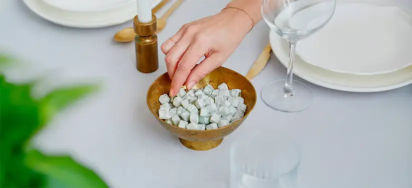 Her ses et fint opdækket bord, hvor der i midten står en guld skål med Wally and Whiz slik i. Der er en kvindehånd, som tager et stykke.