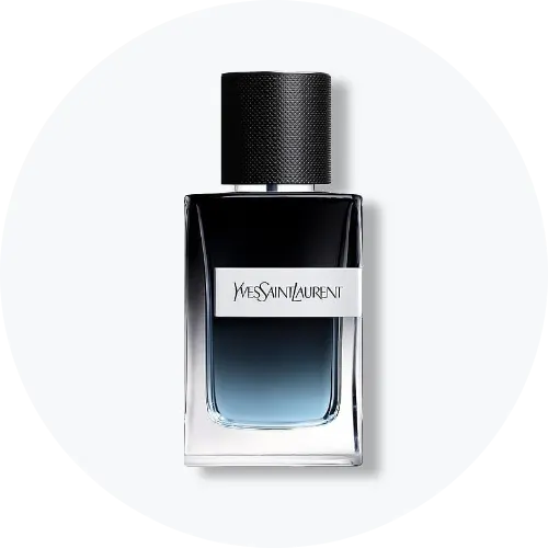 Her ses et billede af en parfumeflakon fra Yves Saint Laurent placeret centralt mod en lys, rund baggrund. Flakonen er i mørkeblå til sort gradient med sort låg og sølvfarvet label med teksten “Yves Saint Laurent”.
