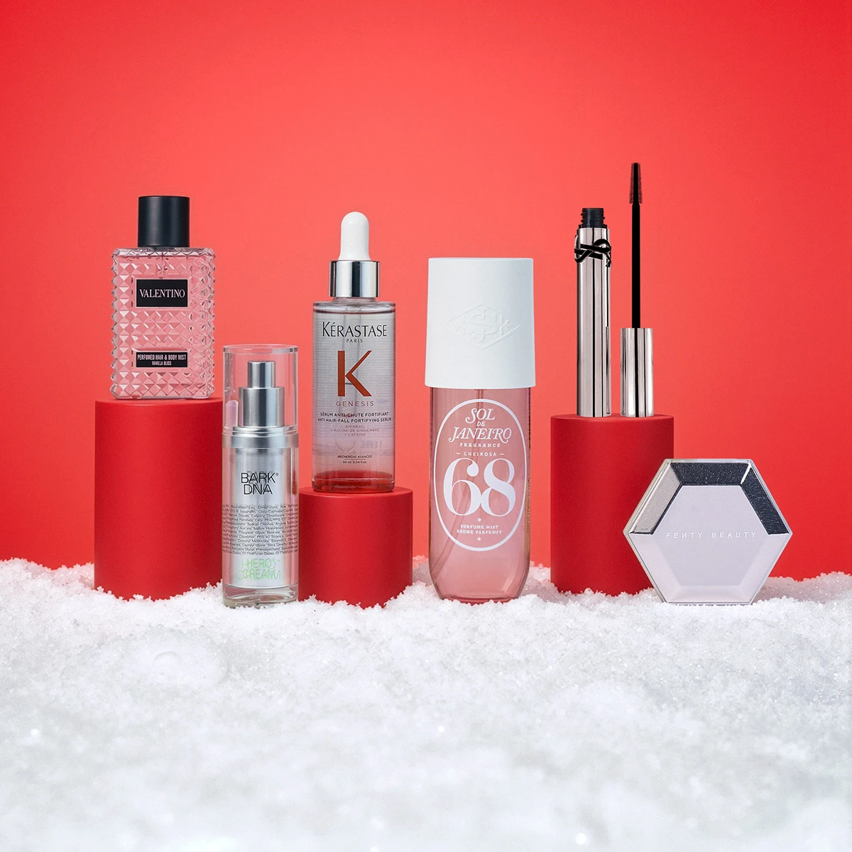 Seks skønhedsprodukter på røde podier med sne: Valentino, Bark DNA, Kérastase, Sol de Janeiro, YSL, Fenty Beauty.