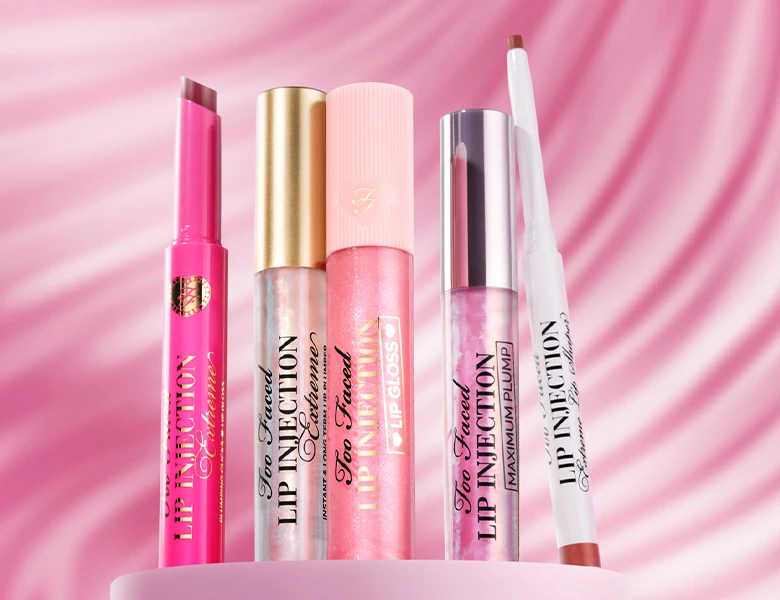 Her ses et billede med forskellige læbeprodukter fra Too Faced placeret mod en pink baggrund. På produkterne står teksten “Lip Injection”.