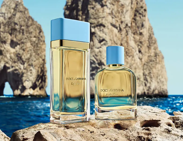 To Dolce & Gabbana Light Blue parfumer med lyseblå låg står på klipper ved havet foran store kystklipper